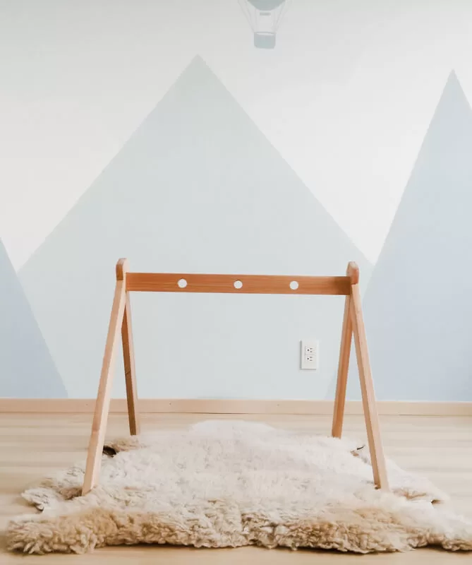 Gimnasio para bebé de madera color natural sobre azalea de borrego