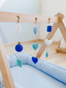 Móvil sensorial para bebé colocado en gimnasio de madera, ideal para estimular los sentidos y el desarrollo temprano.