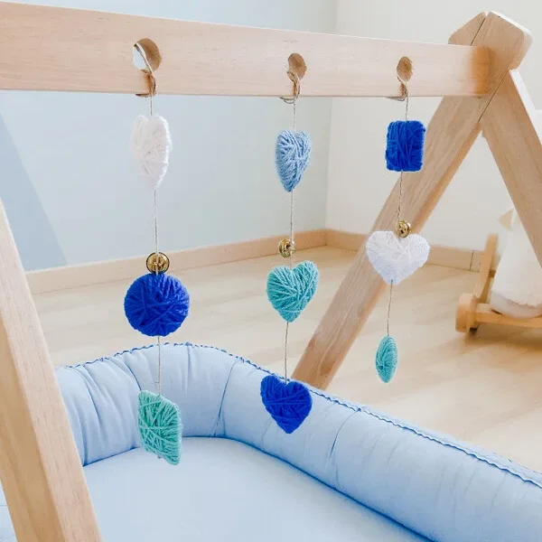 Móvil sensorial para bebé colocado en gimnasio de madera, ideal para estimular los sentidos y el desarrollo temprano.