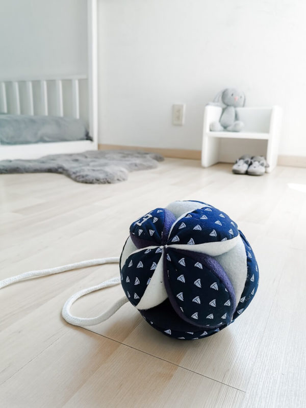 Pelota Montessori azul marino con pequeños barcos combinada con dos tonos de tela