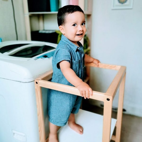 Niño pequeño en Torre Montessori frente a una lavadora