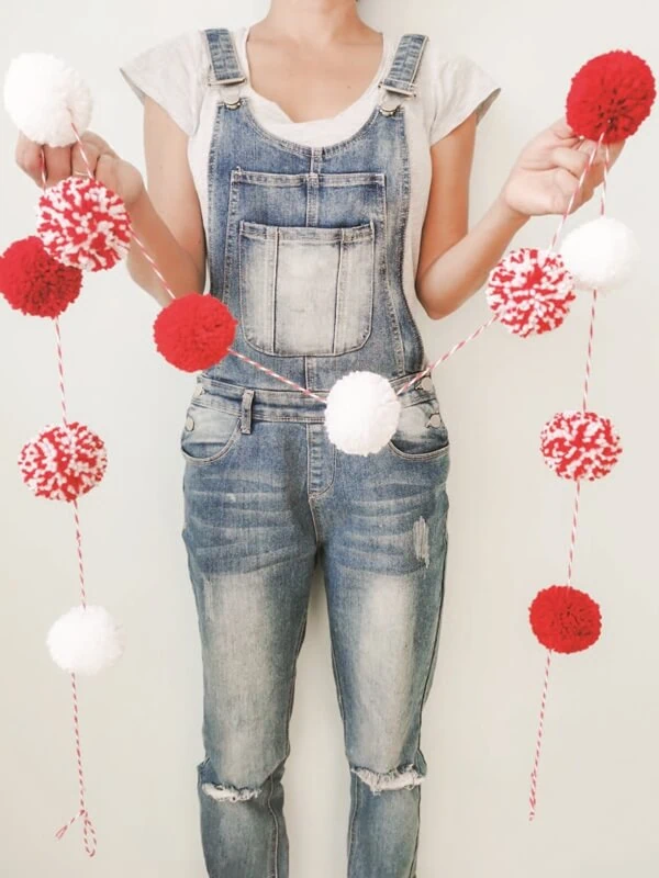 guirnalda-pompones-rojos-blancos-decoracion-navidad Guirnalda de pompones rojos y blancos sostenida por persona, adorno artesanal ideal para decoración de Navidad