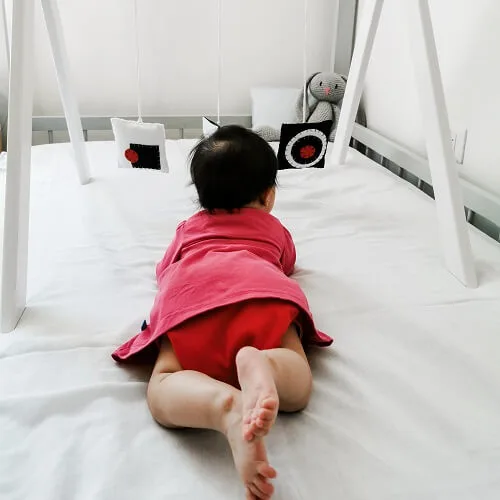 Tummy time de una bebé mirando a figuras geometricas de fieltro