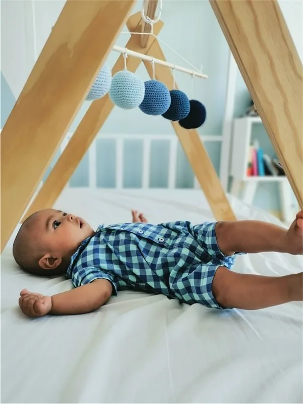 Bebé acostado mirando un móvil Montessori azul, ideal para la estimulación visual bebés durante sus primeras etapas de desarrollo.