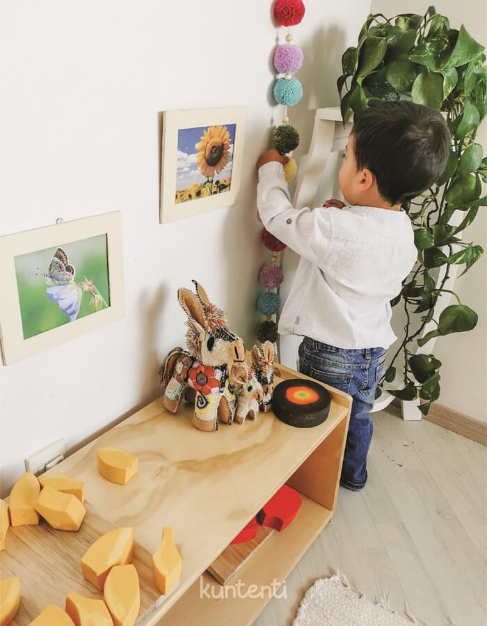 Niño pequeño interactuando de forma autónoma con materiales en un shelf para niños Montessori, fomentando la autonomía infantil en un ambiente preparado