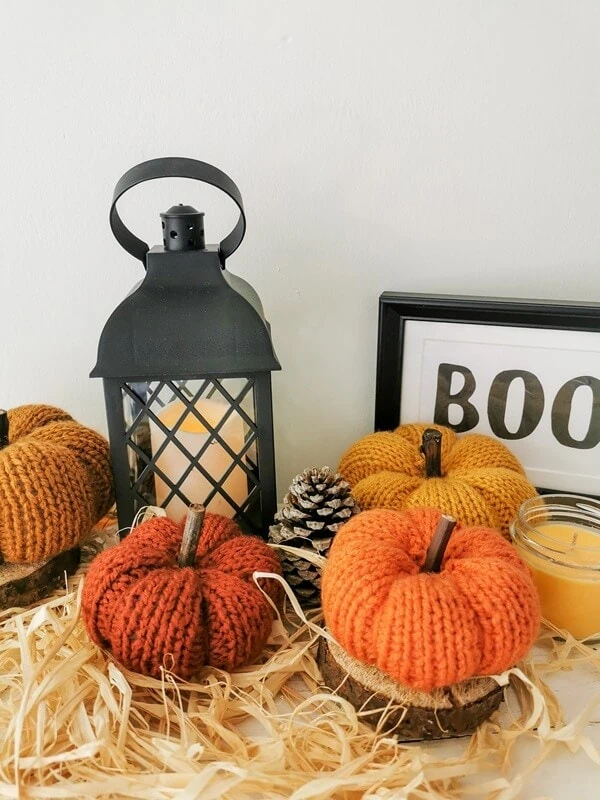 calabazas-para-decoracion-de-otoño Decoración de Halloween con calabazas tejidas en colores naranja y mostaza, acompañadas de faroles y piñas