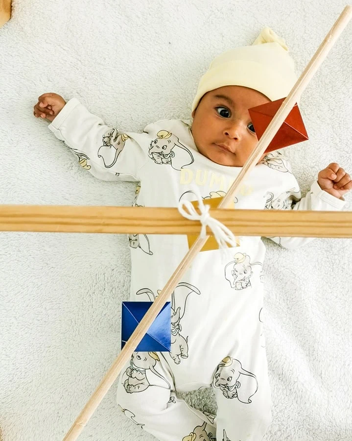 Bebe en sesión de estimulación sensorial mirando fijamente un movil con colores primarios